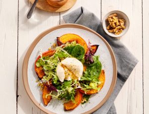 Babyleaf-Salat mit Ahorn-Dressing, Burrata und Nüssen auf Hokkaidospalten