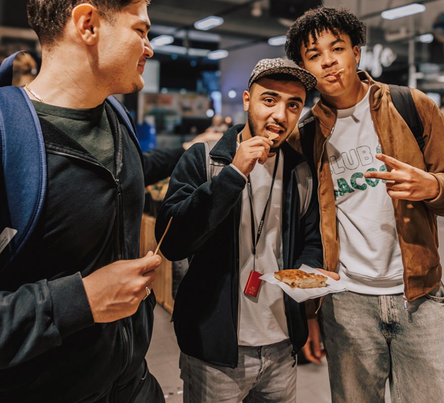 Drei junge Männer verkosten eine Waffel mit Ahornsirup