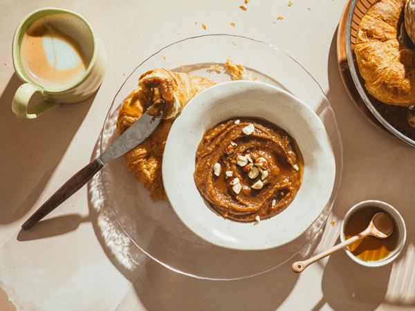 Schälchen mit Ahorn-Nuss Nougat Creme dunkler Nuss-Nougat-Creme, daneben Croissants, Kaffee und Ahornsirup