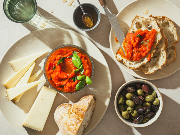 Ahorn-Tomaten Salsa mit Brot, Käse und Oliven auf einem Tisch.