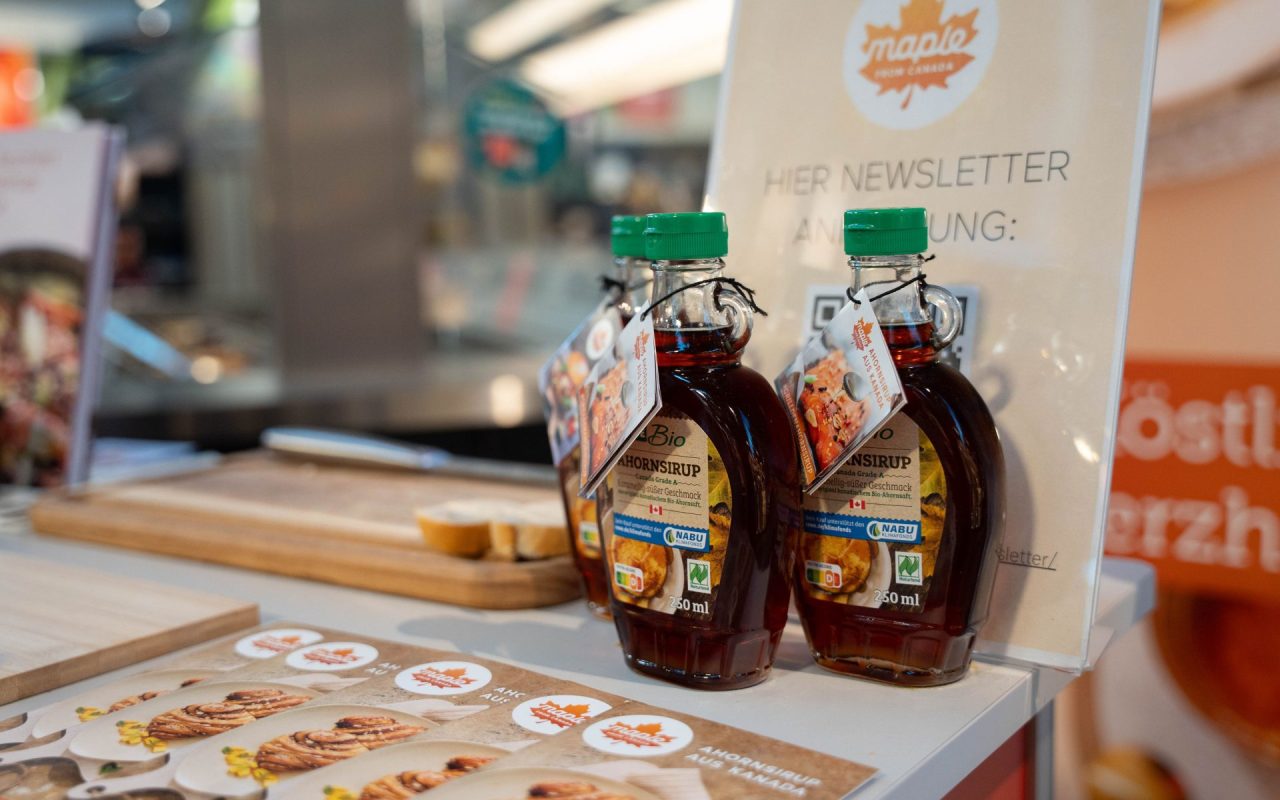 3 Flaschen Ahornsirup aus Kanada und mehrere Prospekte "Maple Brunch" beim Verkostungsstand